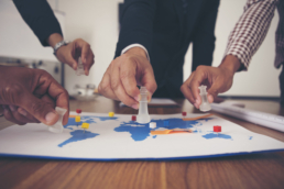 ORM and outsourcing relationship management software illustration: the hand of a group of businessmen holding chess and putting on a map. Concept of businessmen are planning to expand their markets to other countries.