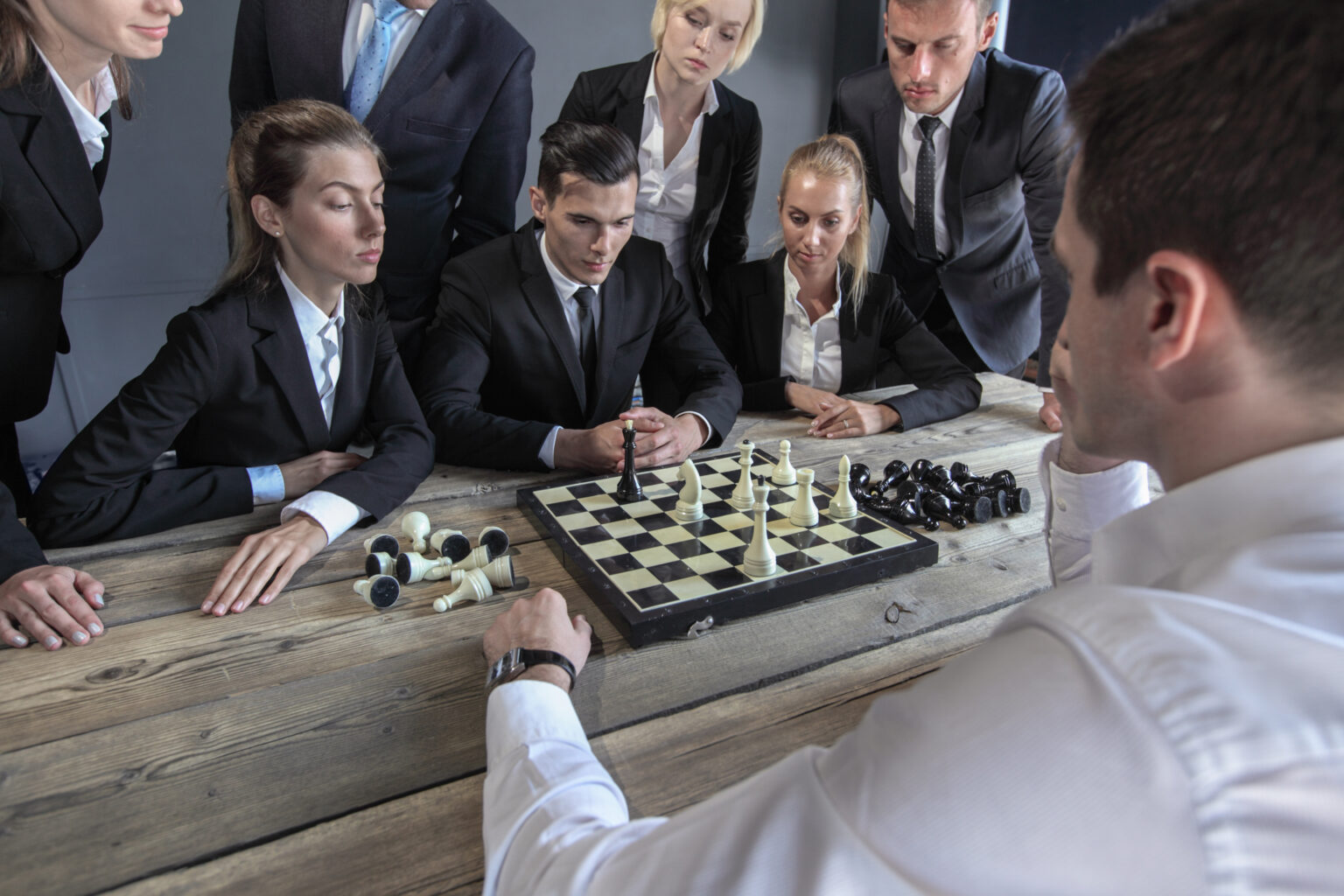 There are business people playing chess, team of workers losing, leader is winning, all that representing business intelligence matter, the fact to take decisions based on data and insights