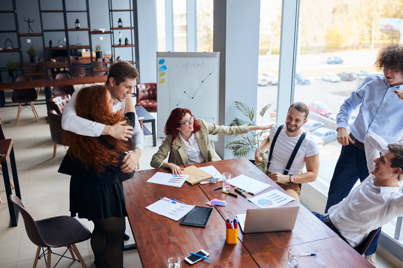 There is a cheerful group of happy business people after winning in formal wear gesturing, hug each other, representing business intelligence matter