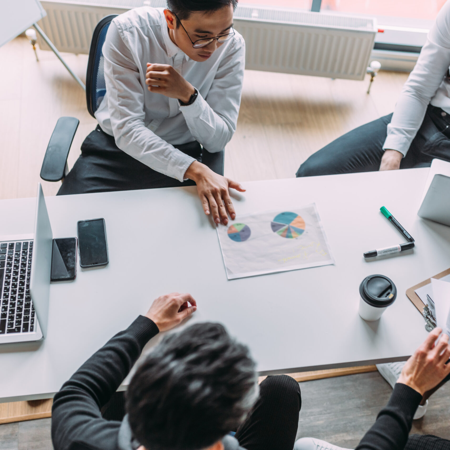 Second Business Plan: Multiracial group of young people in formal wear making out business plan for future start-up project sitting at the desk. Corporate Work Concept . Top view.