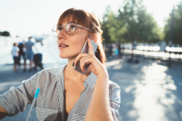 Forms & Field page illustration: pretty caucasian woman in eyeglasses looking up making call on smartphone spending time outdoors, beautiful female millennial talking on mobile phone pondering during conversation on urban settings