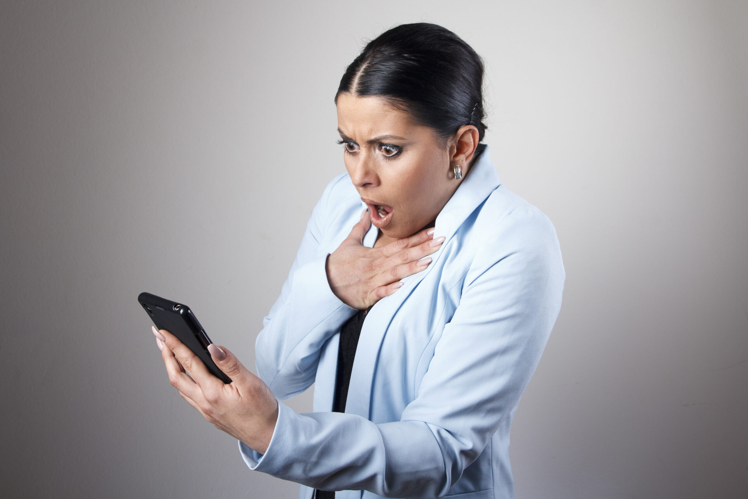 Controversial Statements illustration: young corporate business woman shocked with a message she receives on her cell phone