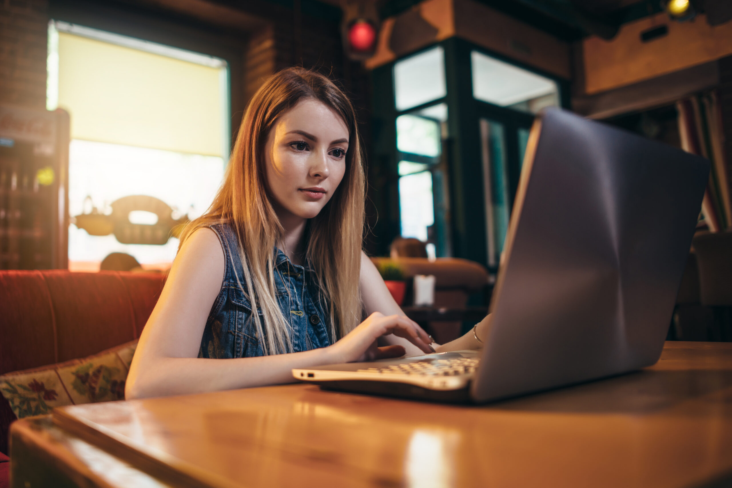 Downloads page illustration: Top view of young female student working on laptop sitting at table.