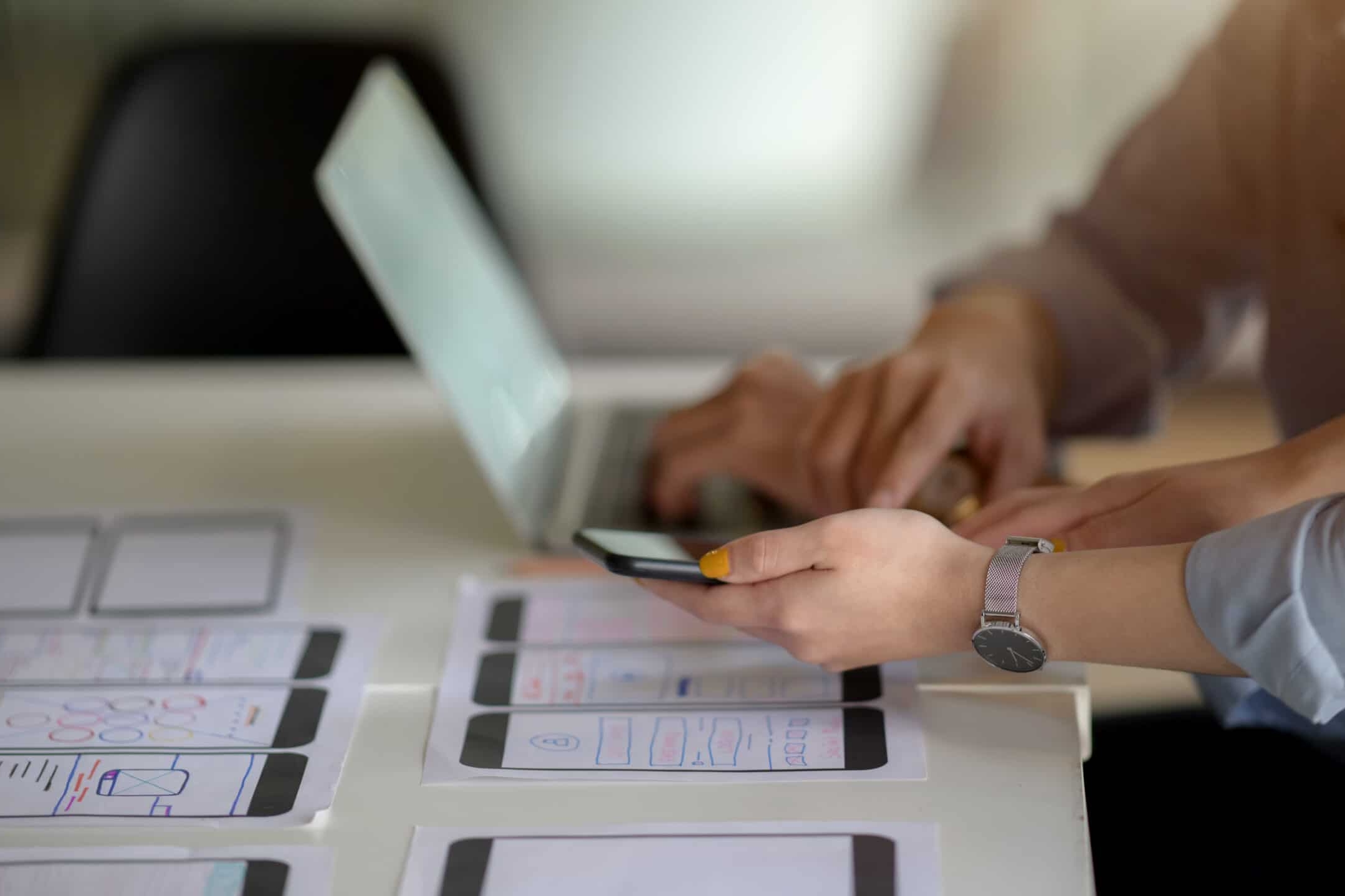 End-User Licence Agreement: side view of UI developer working on laptop and document on white desk while consulting with co worker in simple office room