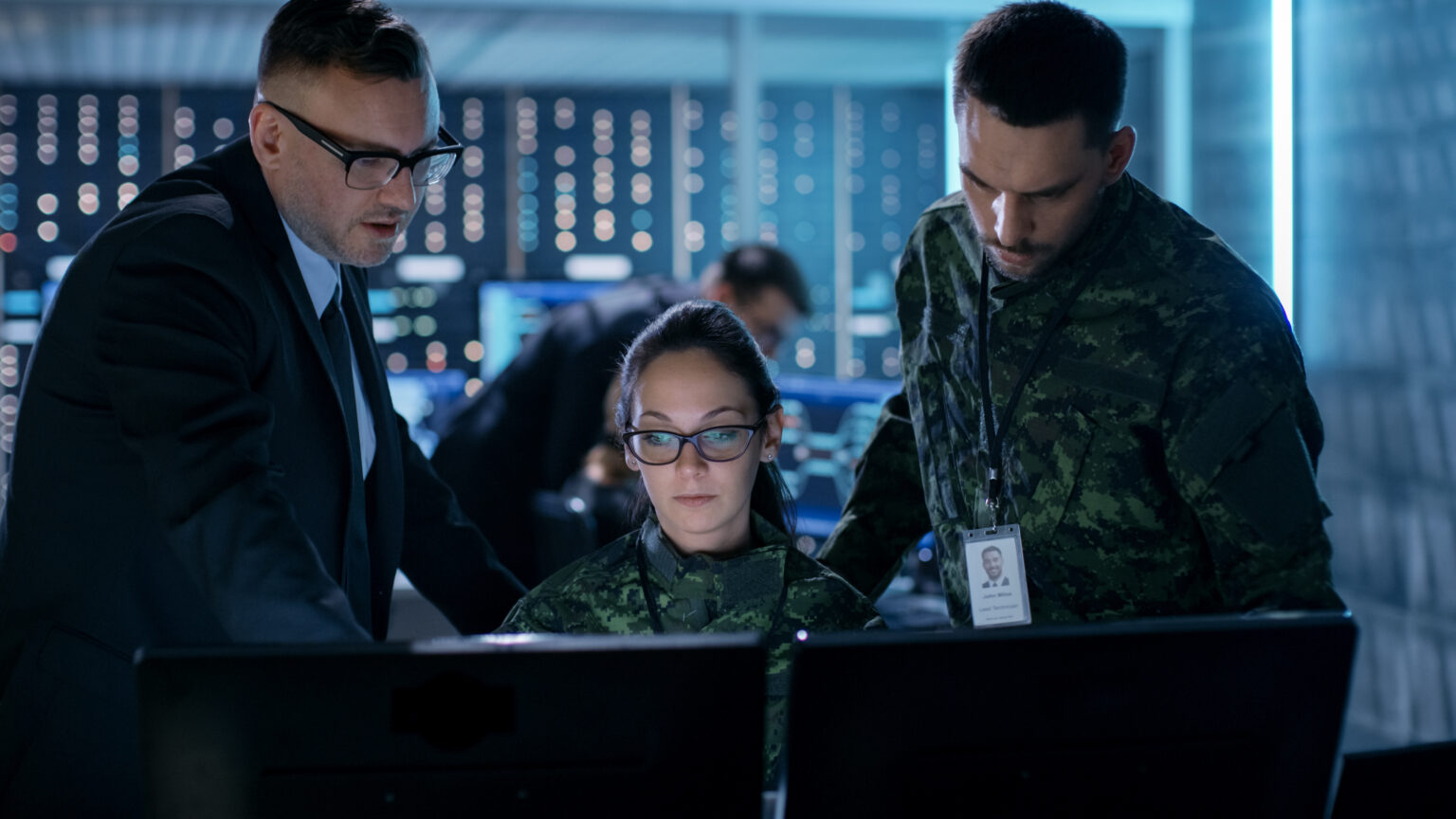 This is about a government surveillance agency and military joint operation. male agent, female and male military officers working at system control center, illustrating Information Security topic