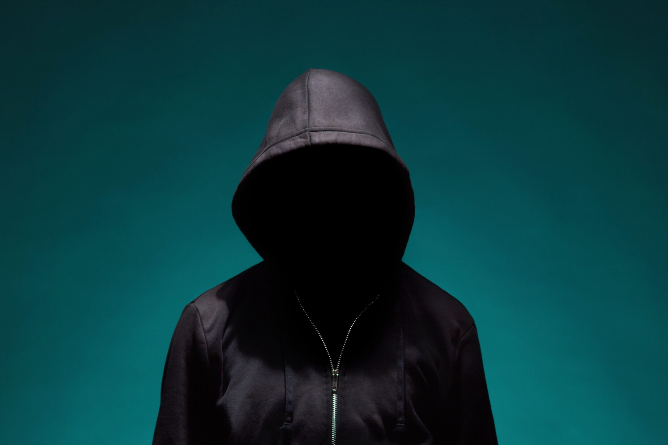 Illustrating Information Security topic : a portrait of computer hacker in hoodie. obscured dark face. data thief, internet fraud, darknet and cyber security concept