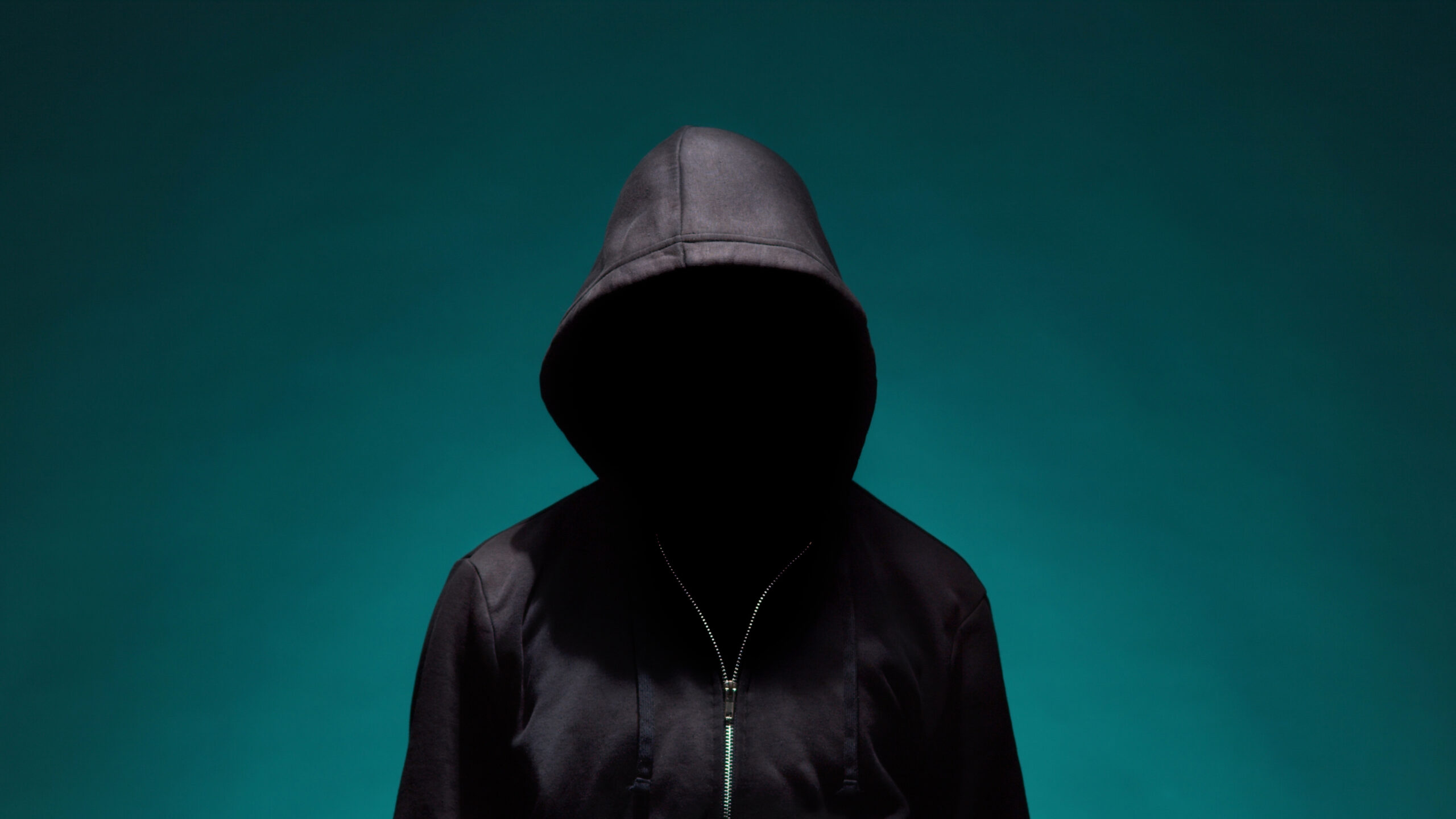 Illustrating Information Security topic : a portrait of computer hacker in hoodie. obscured dark face. data thief, internet fraud, darknet and cyber security concept