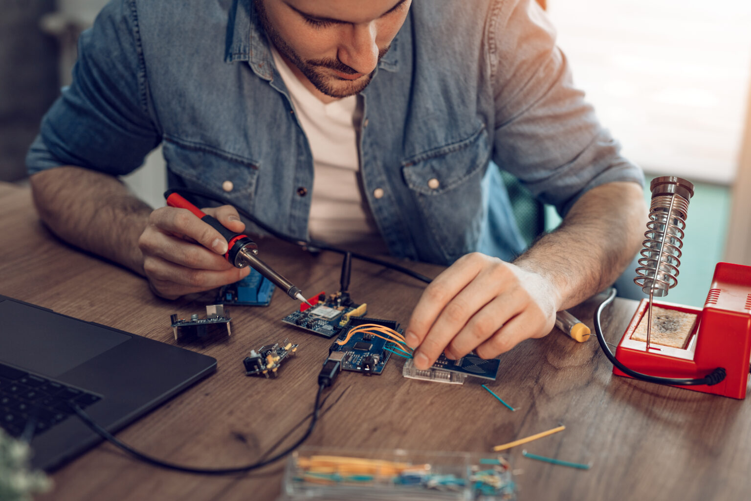 Technician focused on the repair of electronic equipment by soldering iron. illustrating here IoT and Asset Tracking