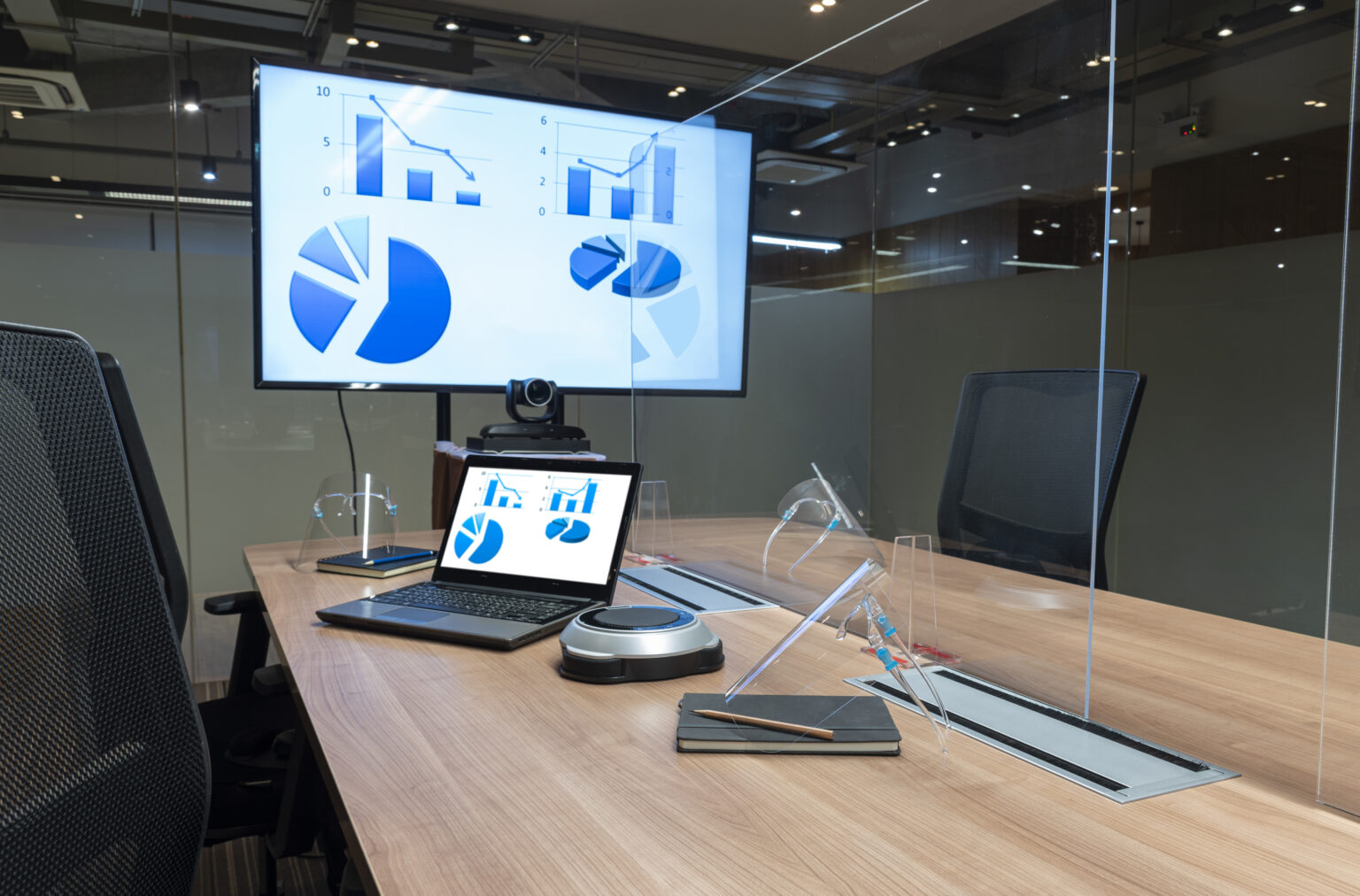 There two screens with charts are displayed in a modern office, illustrating an office suite software, one of the screens is a laptop screen