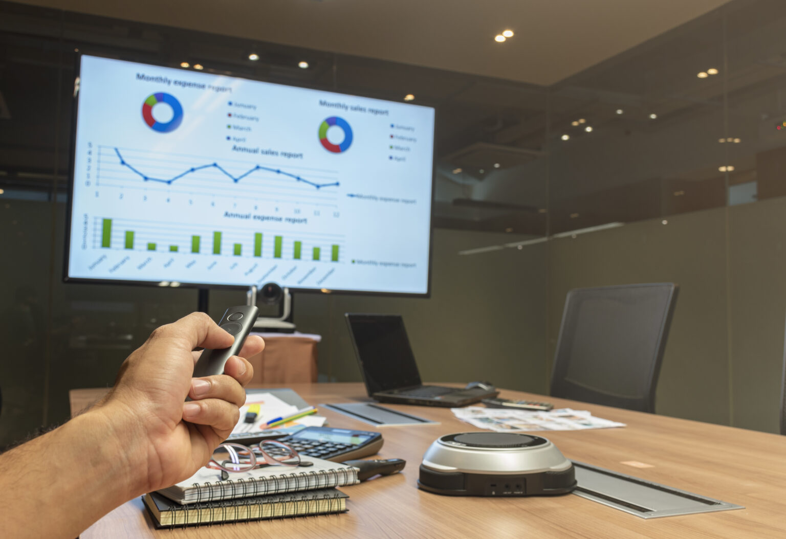 There is a man with a remote controller pointing a screen where charts are displayed, illustrating an office suite software