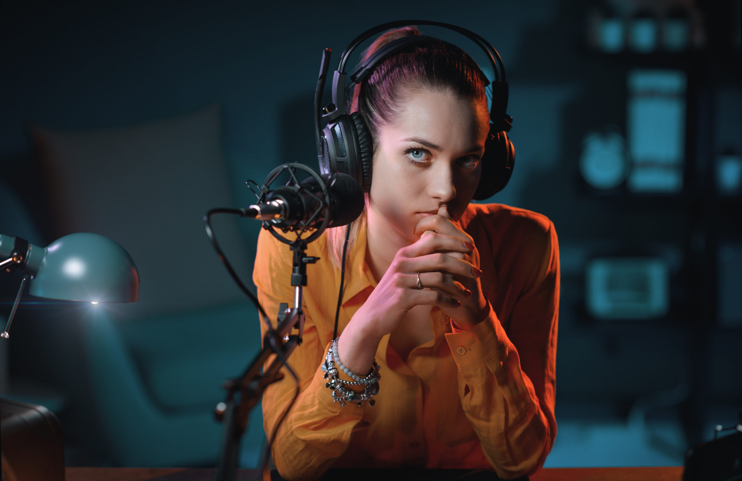 Social networks presence illustration: Young charming radio host sitting in the radio broadcasting studio and looking at camera