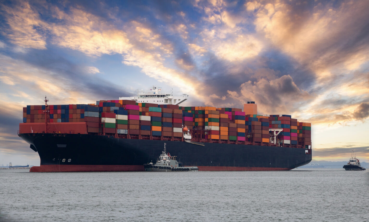 Logistics and container loading by large barges by sea in a harbor full of containers waiting to be transported, for illustrating supply chain management SCM