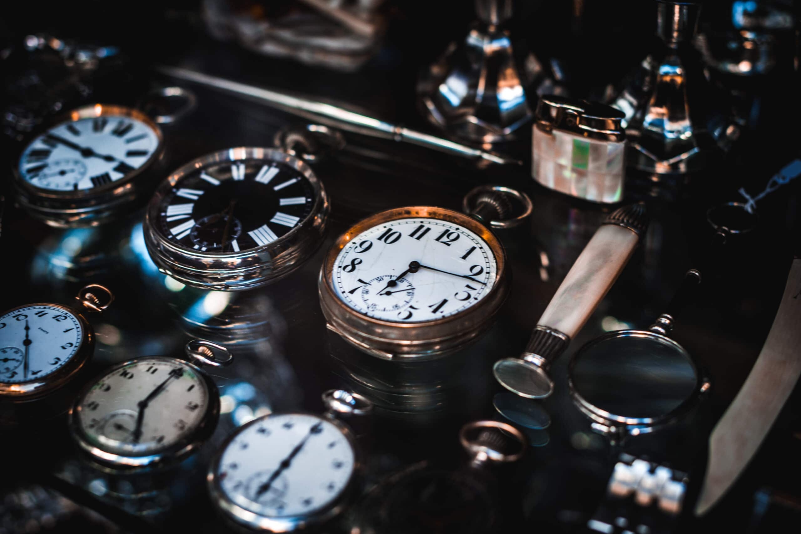 Vintage analog clock surrounded by other vintage cloks in a dark photo