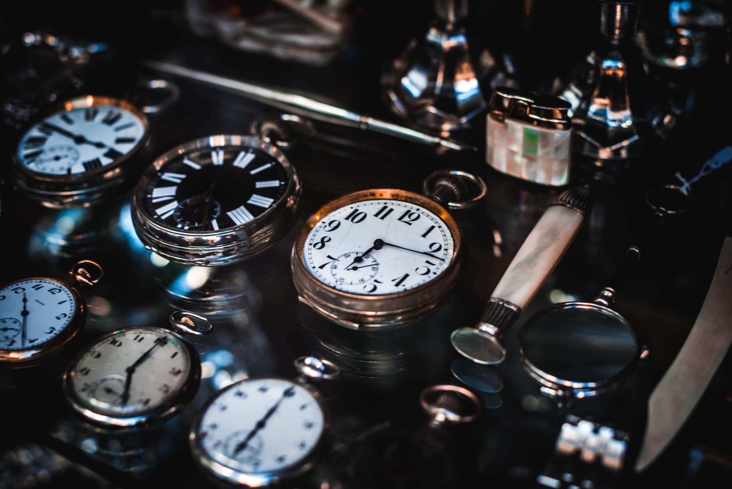 Vintage analog clock surrounded by other vintage cloks in a dark photo