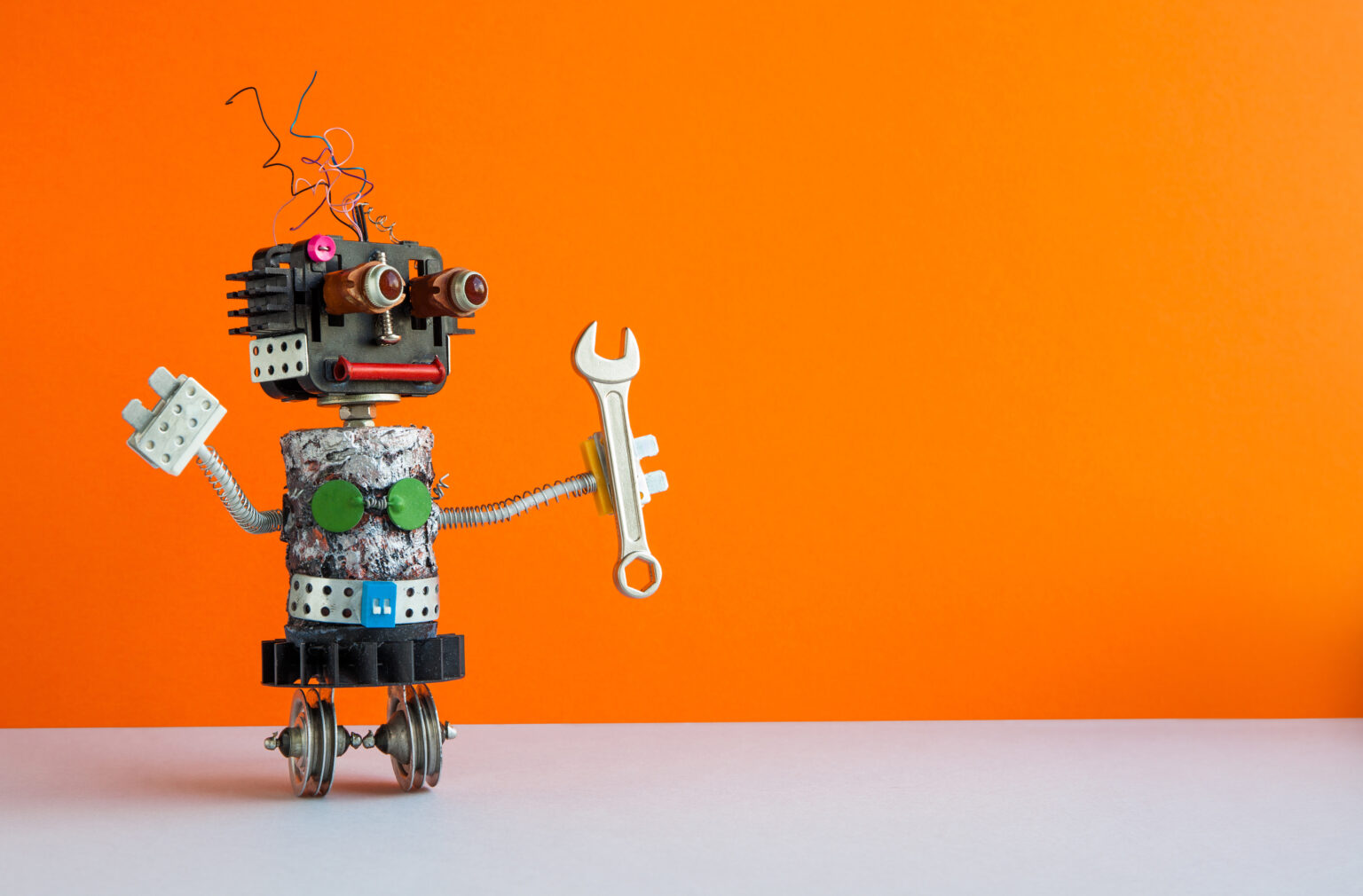 Robot handyman with hand wrench. Fixing maintenance concept. Creative design mechanic two weels robotic character. Orange wall, gray floor background, illustrating here Machine Learning and PHP