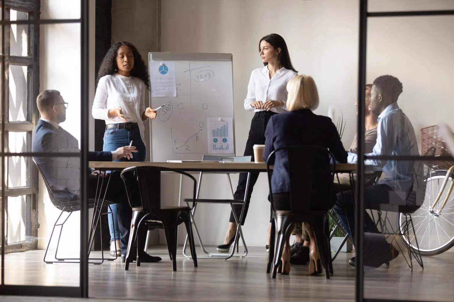 Diverse women startupper making presentation for investors using flip chart illustrating here B2B Sales