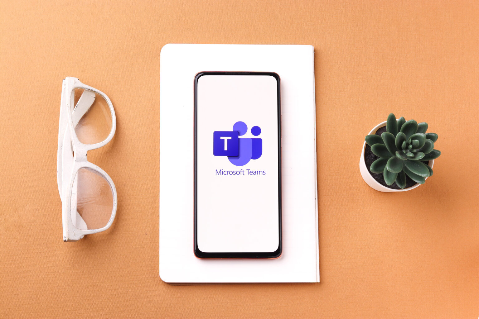 Microsoft teams logo on a table and smartphone, representing Microsoft Teams