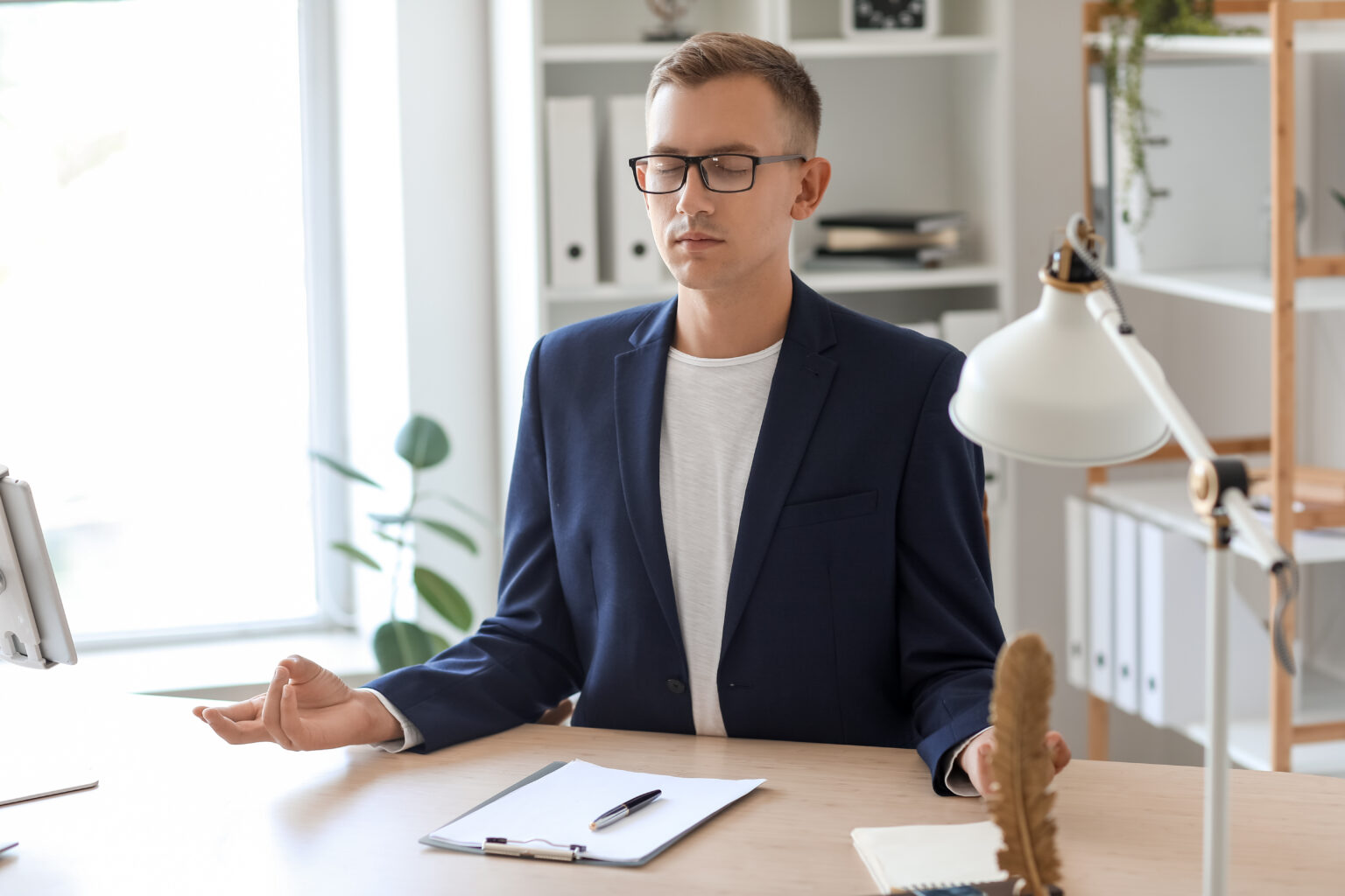 Young man meditating at table in office, illustrating work well-being in the timeNough Founder Institute's elevator pitch